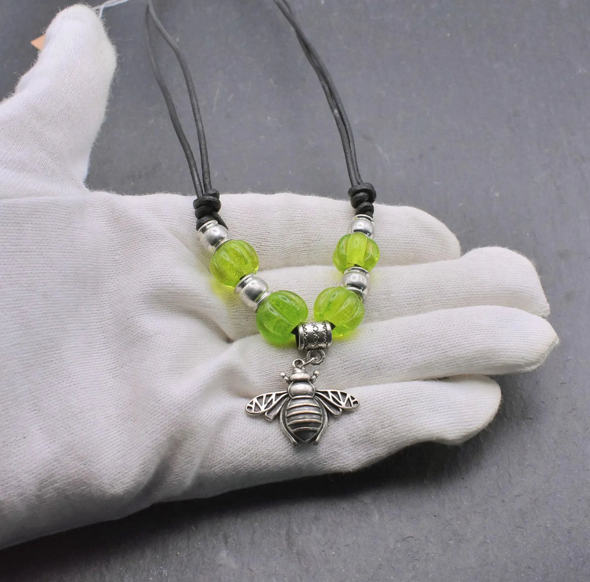 Bienen-Kette "Sumsebienchen" mit grünen Glasperlen auf Lederband auf der Hand
