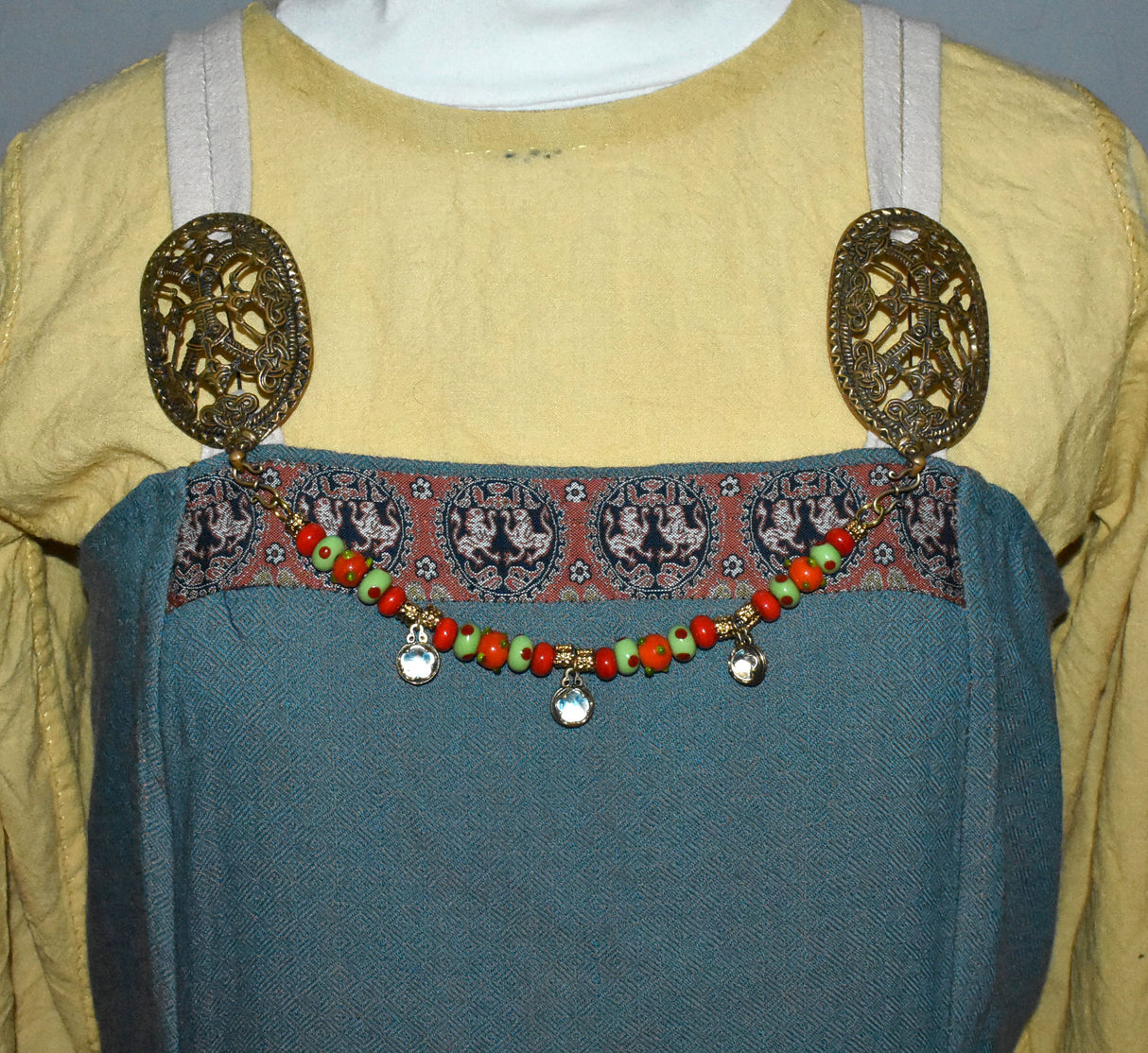 Tragebild am Wikingerkleid der Gotland Fibelkette und Halskette in einem – Handgefertigter Schmuck mit Wikinger-Charme in rot und grün