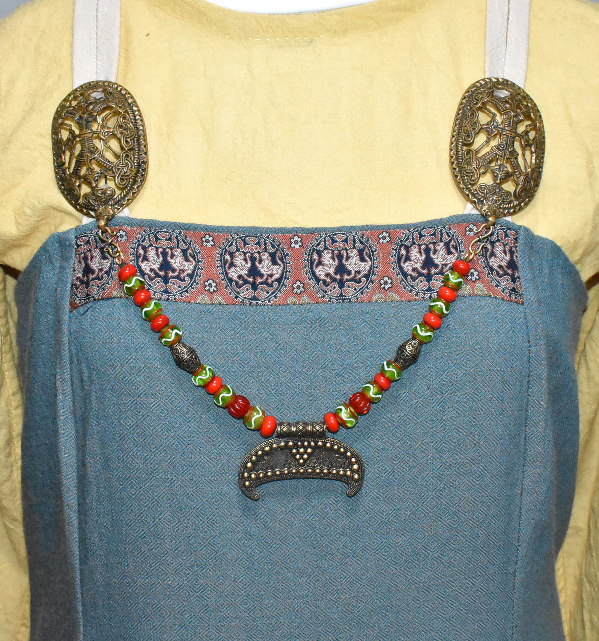 Tragebild am Wikinger Kleid der Slawische Wikinger Fibelkette mit XL Gnedsdovo Lunula aus Bronze – Prunkvolle Glasperlenkette für Wikinger Gewandung in rot und grün
