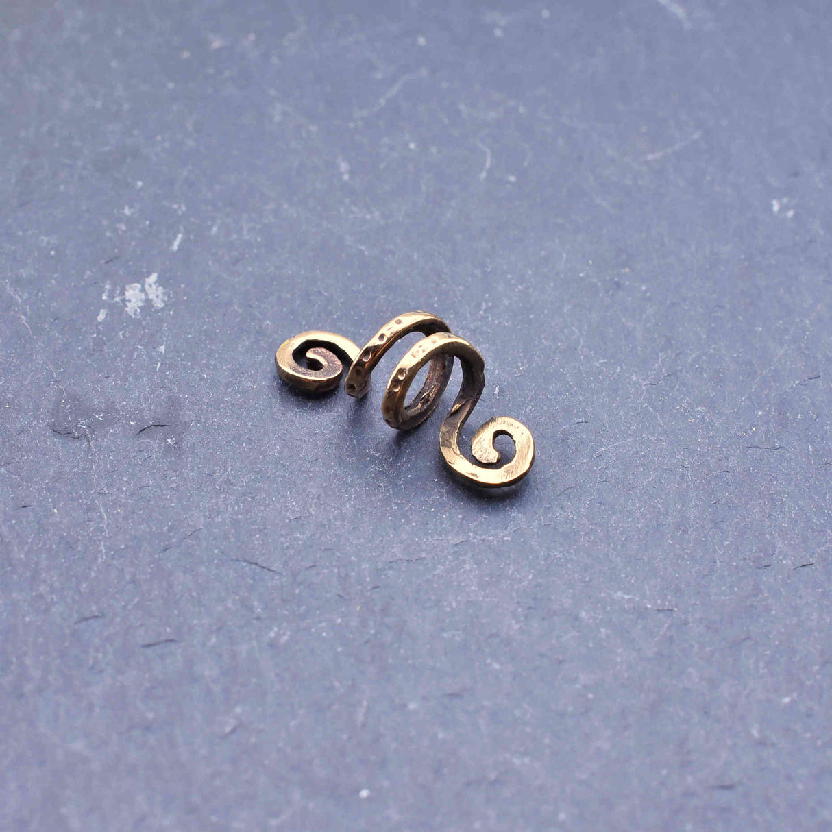 Keltische Spiral-Haarperle aus Bronze auf der Hand