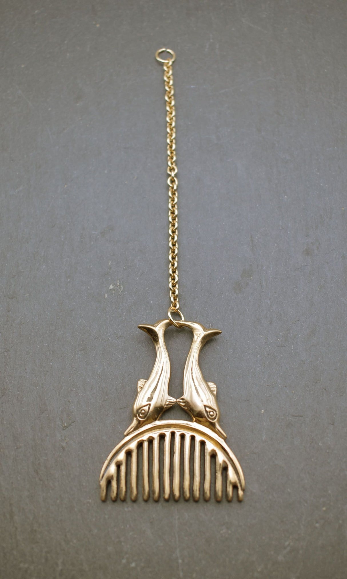 Römischer Bartkamm mit Delphinen aus Bronze an einer Kette