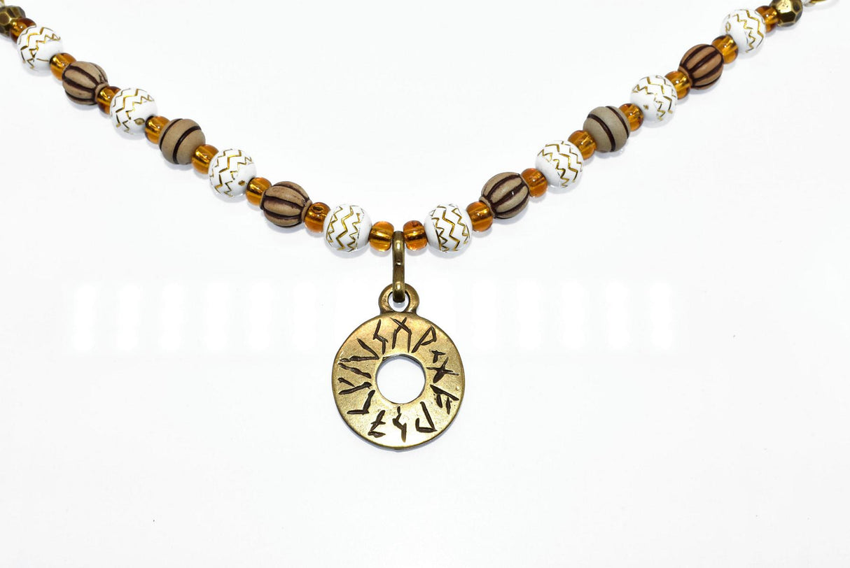 Handgefertigte Runen Fibelkette von BELANAS SCHATZKISTE mit hellbraunen und weißen Acrylperlen, goldfarbenen Mustern, braunen Goldfolienperlen und einem runden Runenamulett aus ZAMAK. Elegantes Design mit mystischem Wikinger-Charme.