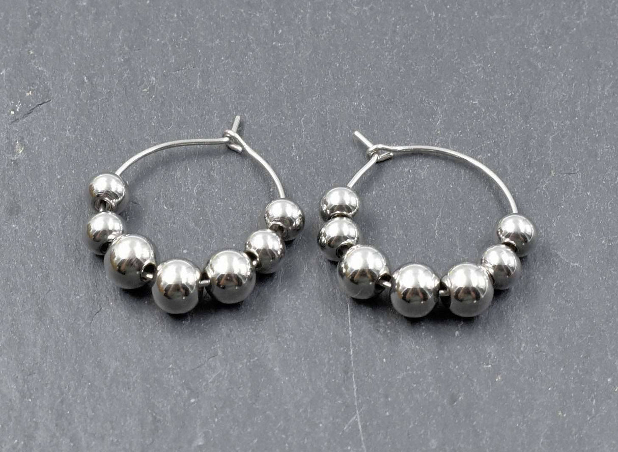 Edelstahl Kreolen mit losen Kugeln silber liegend auf einer Schieferplatte