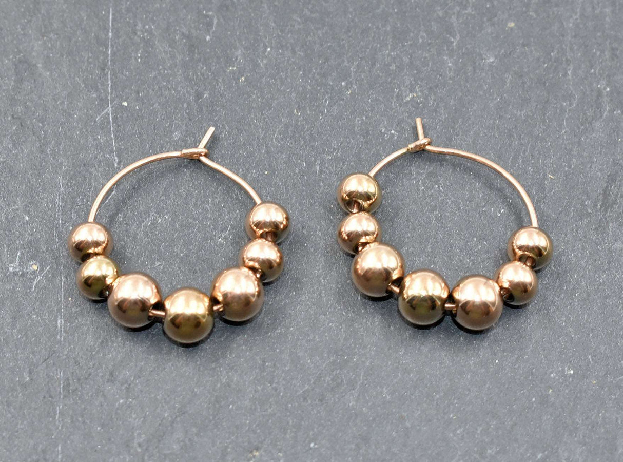 Edelstahl Kreolen mit losen Kugeln goldfarben liegend auf einer Schieferplatte