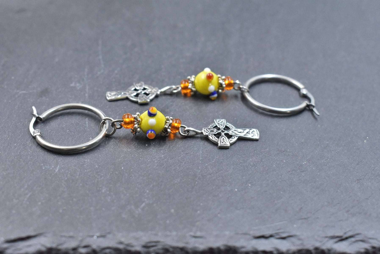 Creolen mit Keltenkreuz mit gelben Lampwork Perlen liegend auf einer Schieferplatte