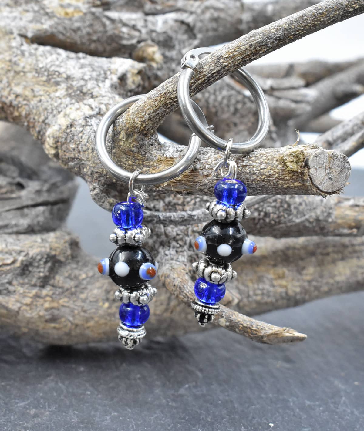 Creolen mit Lampwork Anhänger in schwarz und blau auf einem Ast