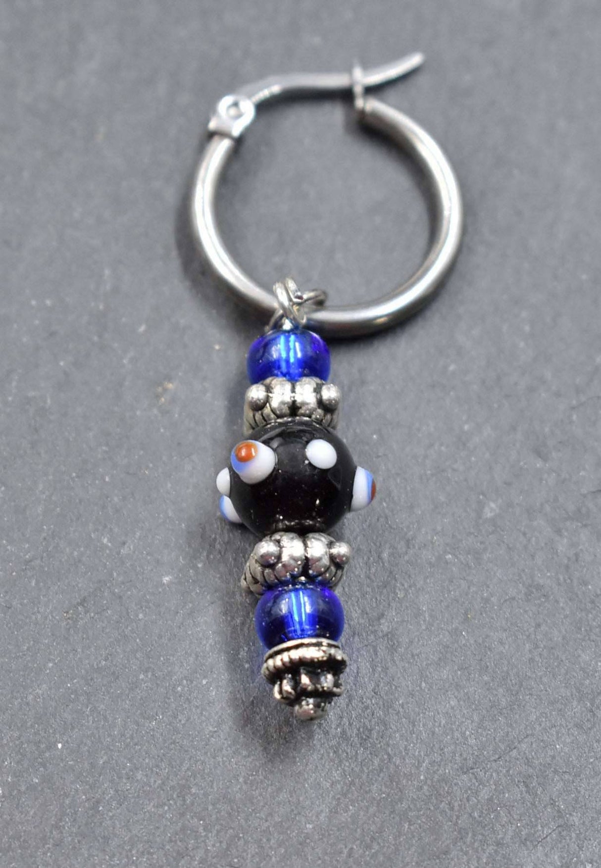 Creolen mit Lampwork Anhänger in schwarz und blau liegend auf einer Schieferplatte