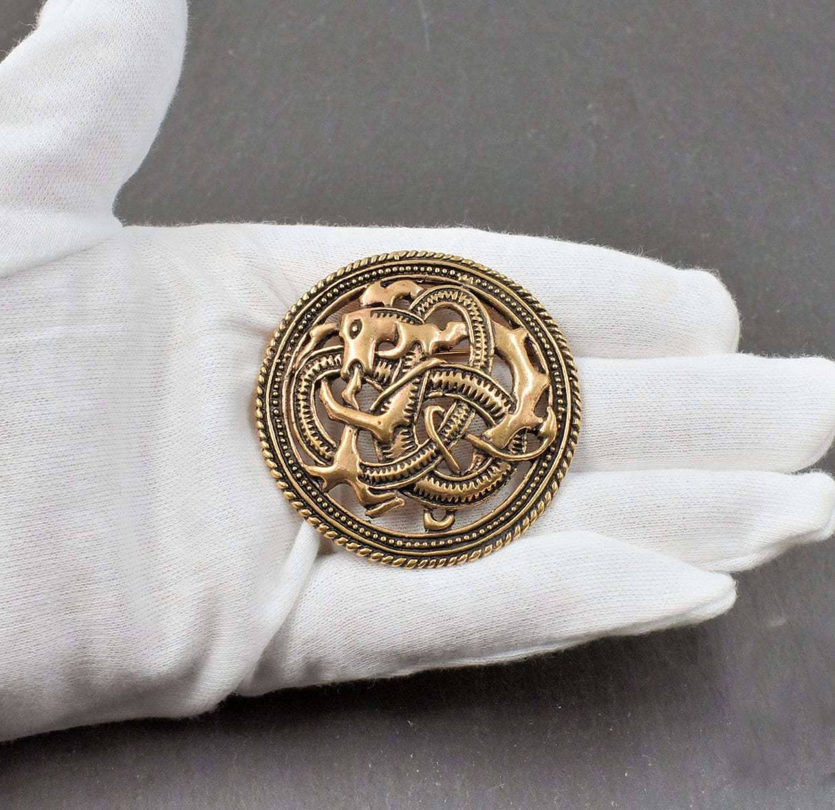 Drachen Brosche im Mammen Stil aus Bronze auf einer Schieferplatte auf der Hand