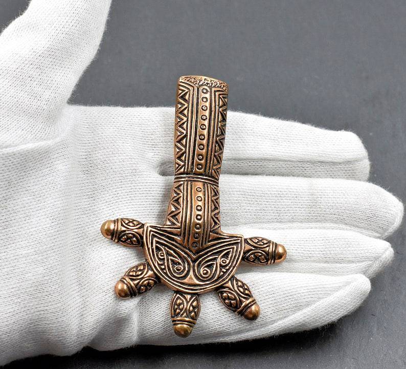 Germanische Ärmchenfibel aus Bronze auf der Hand