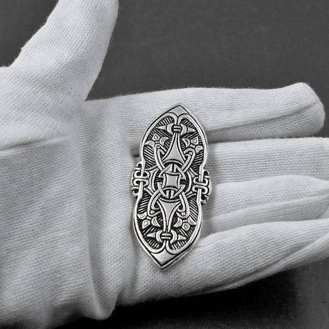 Birka Fibel aus versilberter Bronze auf der Hand