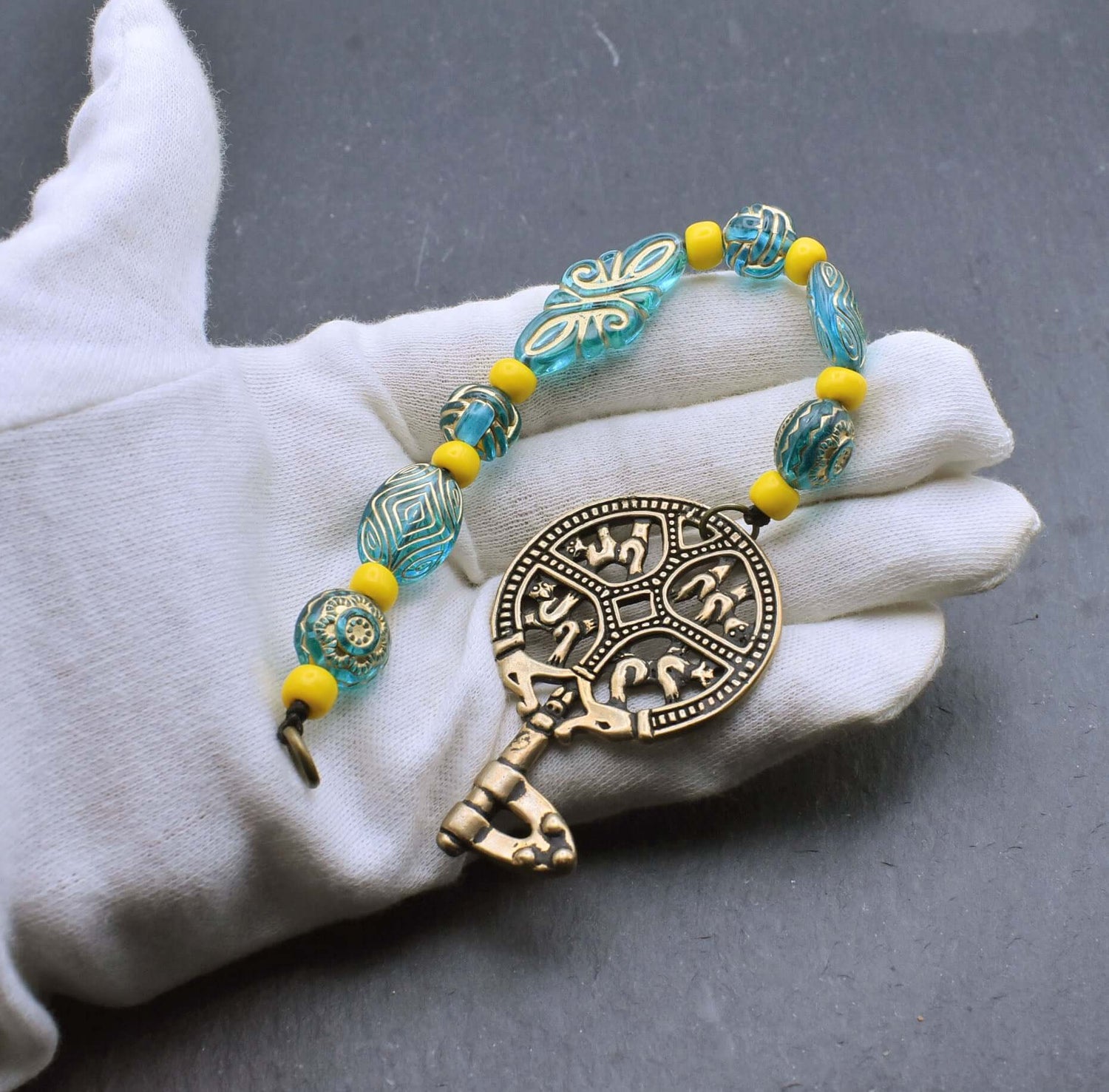 Birka Schlüssel mit Perlenkette in türkis und gelb auf der Hand