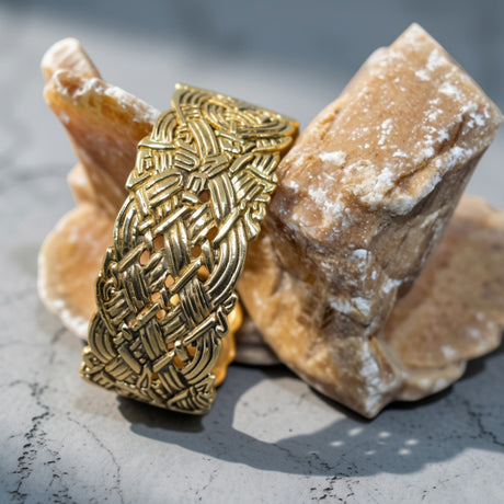 Breiter keltischer Bronze-Armreif mit Flechtmuster

Dieser breite Armreif aus Bronze wird von einem aufwendig durchbrochenen Flechtornament bestimmt. Zahlreiche Bänder verschlingen sich miteinander und bilden ein dichtes Knotenmotiv, das fast die gesamte Vorderseite des Armreifs einnimmt.