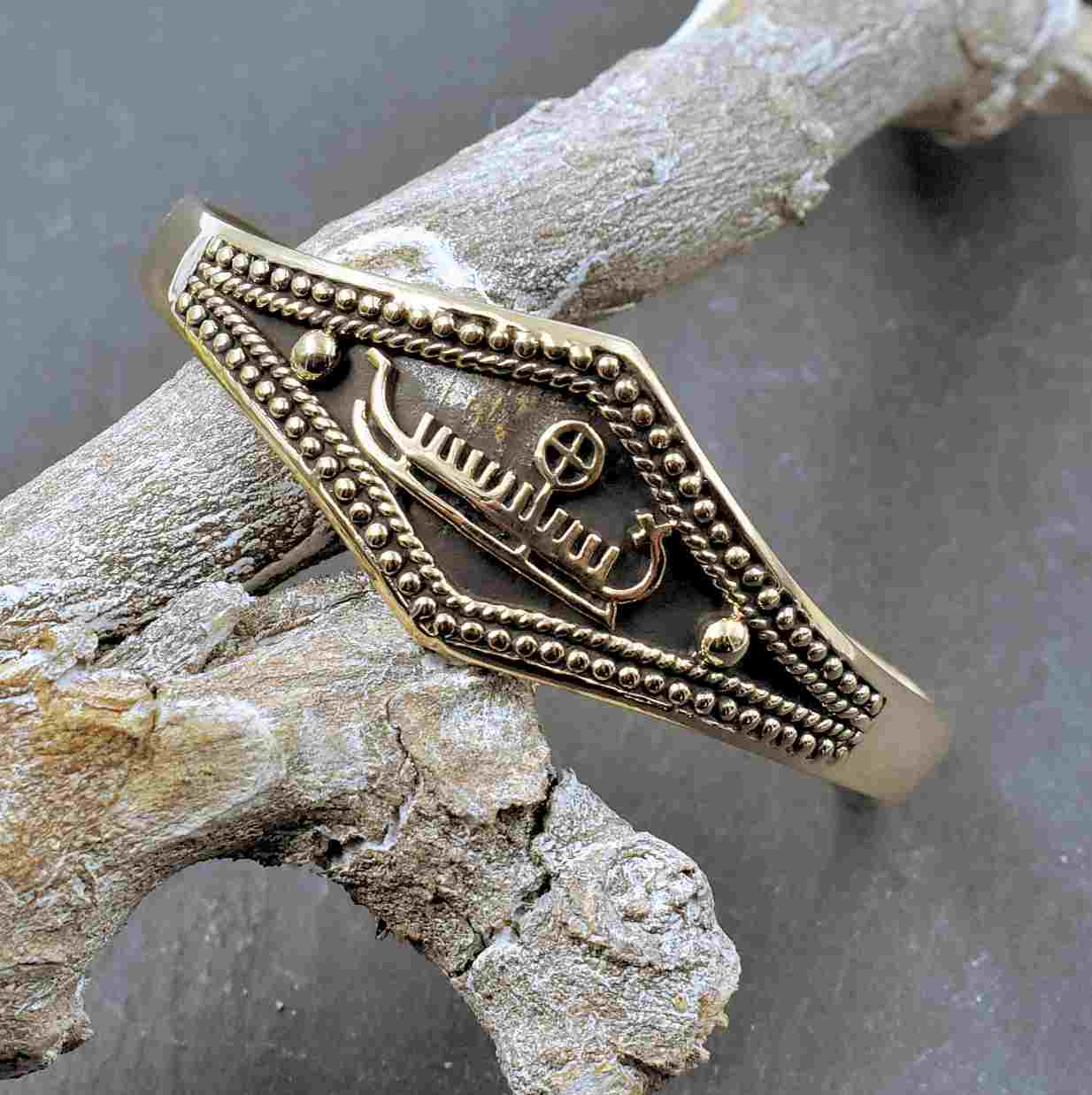 Wikinger Armreif aus Bronze mit Wikingerschiff

Dieser Wikinger Armreif aus Bronze mit Wikingerschiff zeigt auf seiner breiten Vorderseite ein stilisiertes Langschiff mit hochgezogenen Steven. Plastische Punktreihen und kordelartige Ornamente rahmen das Schiff ein und setzen sich bis zu den schmaleren Seiten des offenen Armreifs fort.