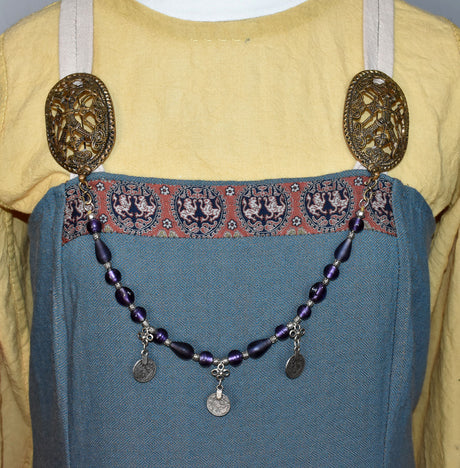 Tragebild am Wikinger-Kleid der Wikinger Fibelkette „Majvi“ mit orientalischen Münzen und lila Glasperlen
Nordische Gehängekette für Schürzenkleid und historische Gewandung