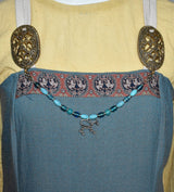 Tragebild an einem Wikinger Kleid der Wikinger Fibelkette mit Pferdeanhänger und türkis-blauen Perlen – Nordische Glasperlenkette für Wikinger Gewandung