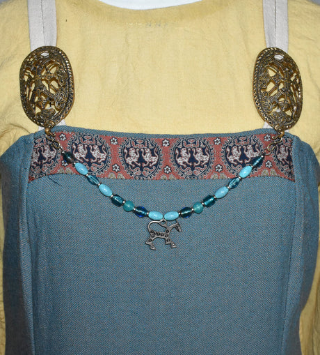 Tragebild an einem Wikinger Kleid der Wikinger Fibelkette mit Pferdeanhänger und türkis-blauen Perlen – Nordische Glasperlenkette für Wikinger Gewandung