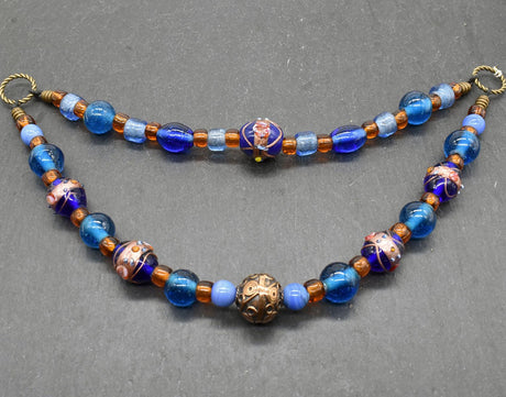 Handgefertigte Fibelkette aus blauen und goldbraunen Glasperlen mit bronzefarbenen Metallringen, perfekt für Wikingerkleidung und Reenactment, gefertigt von Belanas Schatzkiste.