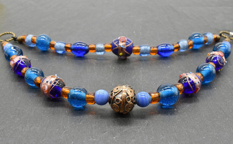 Handgefertigte Fibelkette aus blauen und goldbraunen Glasperlen mit bronzefarbenen Metallringen, perfekt für Wikingerkleidung und Reenactment, gefertigt von Belanas Schatzkiste.