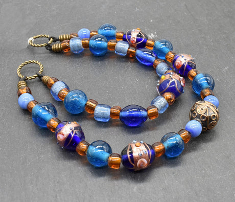 Handgefertigte Fibelkette aus blauen und goldbraunen Glasperlen mit bronzefarbenen Metallringen, perfekt für Wikingerkleidung und Reenactment, gefertigt von Belanas Schatzkiste.