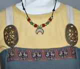 Tragebild am Wikinger Kleid der Historische Lunula Halskette VENUS aus Bronze mit handgefertigten roten und grünen Glasperlen. Perfekt für Mittelalter, Reenactment und LARP. Verstellbares Lederband, authentischer römischer Schmuck.