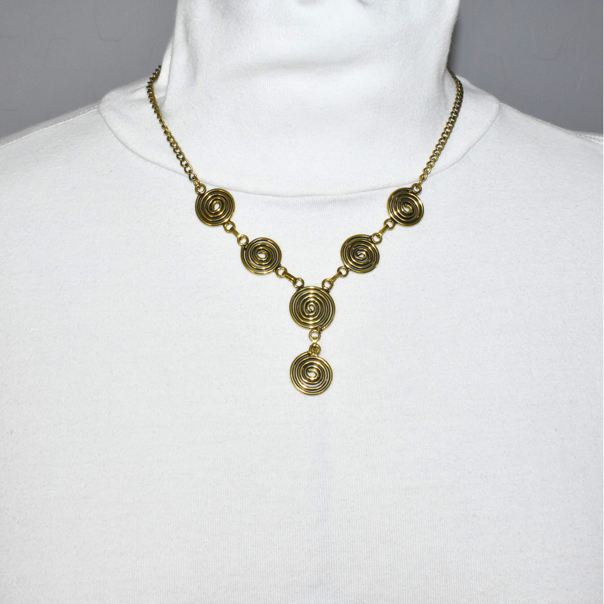 Die Keltische Bronzekette Alin ist ein handgefertigtes Schmuckstück aus hochwertigem Bronzedraht. Das Design besticht durch elegante, runde Spiralen, die mit filigranen Kettengliedern verbunden sind. Der edle bronzene Farbton verleiht der Kette eine zeitlose, mystische Ausstrahlung. Mit einer Länge von etwa 53 cm und einem praktischen Hakenverschluss eignet sich die Kette perfekt für den Alltag oder als besonderes Accessoire zu eleganten Outfits wie Blusen oder Rollkragenpullovern. Ideal für alle, die kelti