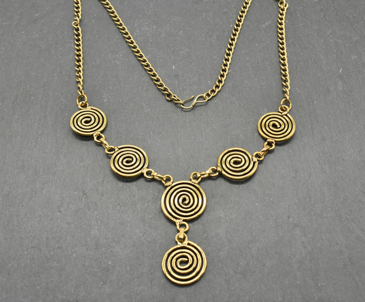 Die Keltische Bronzekette Alin ist ein handgefertigtes Schmuckstück aus hochwertigem Bronzedraht. Das Design besticht durch elegante, runde Spiralen, die mit filigranen Kettengliedern verbunden sind. Der edle bronzene Farbton verleiht der Kette eine zeitlose, mystische Ausstrahlung. Mit einer Länge von etwa 53 cm und einem praktischen Hakenverschluss eignet sich die Kette perfekt für den Alltag oder als besonderes Accessoire zu eleganten Outfits wie Blusen oder Rollkragenpullovern. Ideal für alle, die kelti