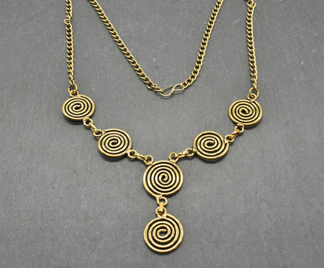Die Keltische Bronzekette Alin ist ein handgefertigtes Schmuckstück aus hochwertigem Bronzedraht. Das Design besticht durch elegante, runde Spiralen, die mit filigranen Kettengliedern verbunden sind. Der edle bronzene Farbton verleiht der Kette eine zeitlose, mystische Ausstrahlung. Mit einer Länge von etwa 53 cm und einem praktischen Hakenverschluss eignet sich die Kette perfekt für den Alltag oder als besonderes Accessoire zu eleganten Outfits wie Blusen oder Rollkragenpullovern. Ideal für alle, die kelti