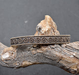 Keltischer Bronzearmreif mit traditionellem Muster auf einem Ast