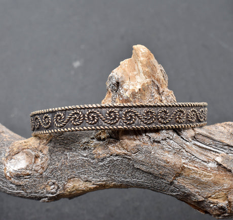 Keltischer Bronzearmreif mit traditionellem Muster auf einem Ast