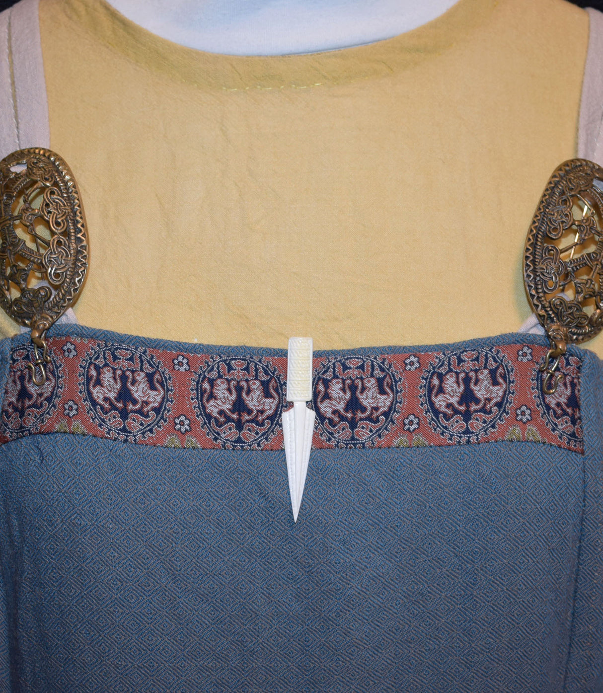 Handgeschnitzte Pfeilspitzen-Krawattennadel und Schal-Klammer aus Rinderknochen an einem Wikingerkleid
