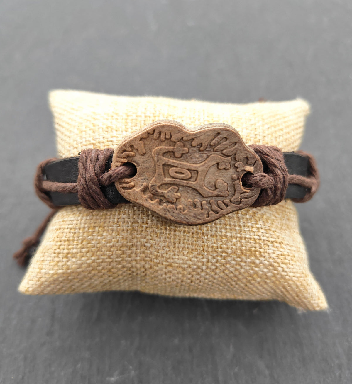 Lederarmband mit Keramik-Motivplatte in Holzoptik auf einem Kissen
