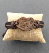 Lederarmband mit Keramik-Motivplatte in Holzoptik auf einem Kissen
