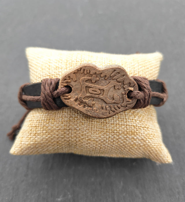 Lederarmband mit Keramik-Motivplatte in Holzoptik auf einem Kissen
