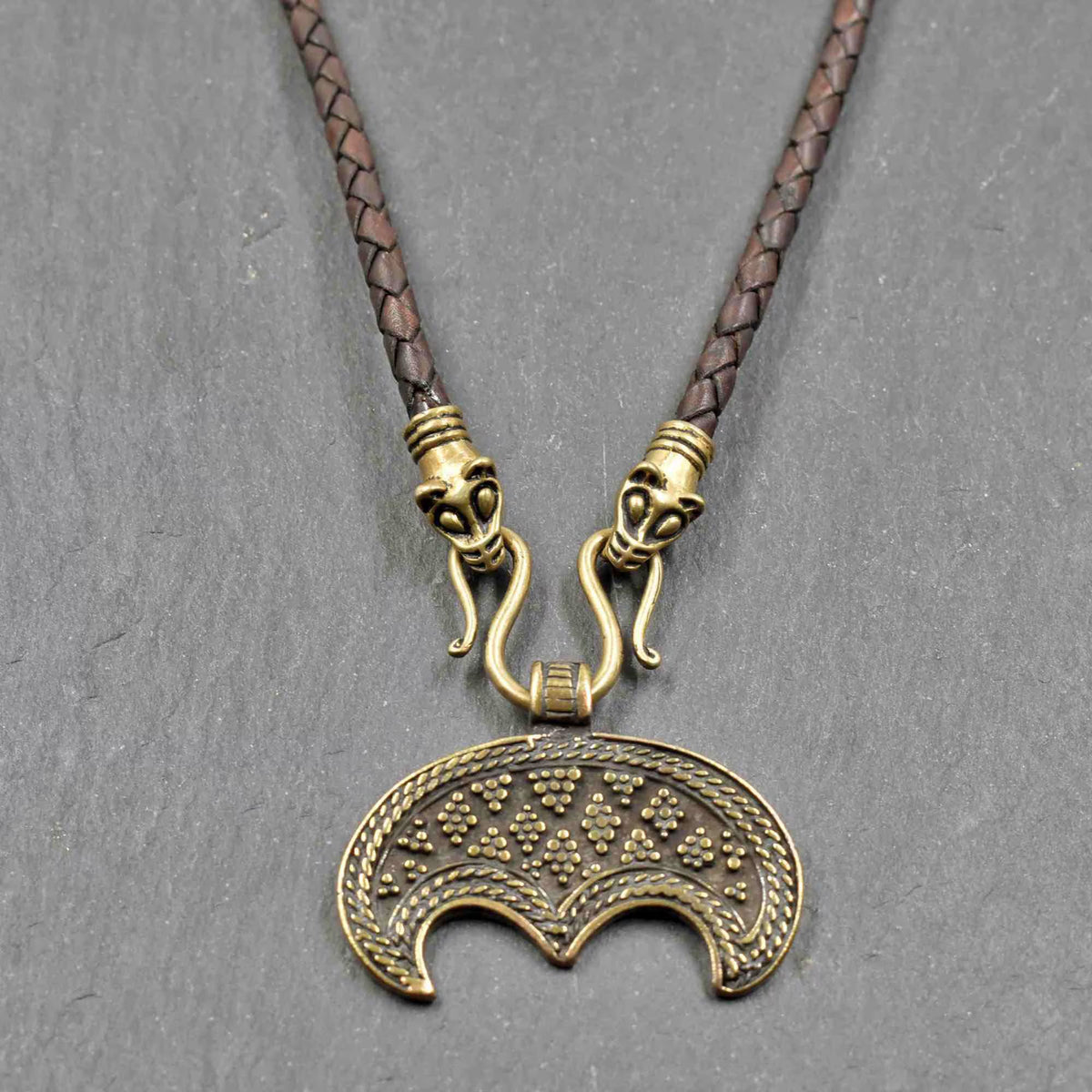 Lunula-Lederkette mit Rabenköpfen

Zwei kunstvoll verzierte Rabenköpfe halten einen Omega-Haken, an dem ein halbmondförmiger Lunula-Anhänger befestigt ist. Die geflochtene Lederkette verbindet damit zwei unterschiedliche historische Schmuckvorbilder aus der Wikingerzeit.