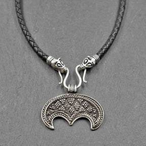 Lunula-Lederkette mit Rabenköpfen

Zwei kunstvoll verzierte Rabenköpfe halten einen Omega-Haken, an dem ein halbmondförmiger Lunula-Anhänger befestigt ist. Die geflochtene Lederkette verbindet damit zwei unterschiedliche historische Schmuckvorbilder aus der Wikingerzeit.