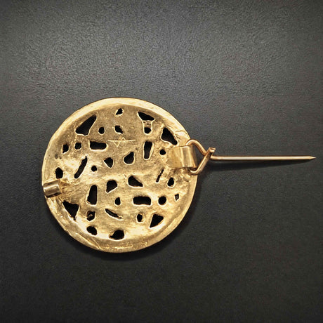 Rückseite mit geöffneter Nadel der Diese Scheibenfibel aus Bronze ist im Borre-Stil gestaltet, einem charakteristischen Kunststil der Wikingerzeit. Das symmetrisch aufgebaute Ornament greift die verschlungenen Tier- und Flechtmotive auf, die für diesen Stil typisch sind.