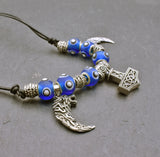 Mjölnir-Kette „Ragnar“ kombiniert drei Anhänger aus 925er Sterling Silber mit kräftig blauen, handgefertigten Glasperlen und schwarzem Lederband.

Im Mittelpunkt sitzt ein reich verzierter Thorshammer. Zwei gebogene, zahnförmige Anhänger mit plastisch ausgearbeiteten Wolfsköpfen flankieren den Mjölnir.