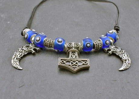Mjölnir-Kette „Ragnar“ kombiniert drei Anhänger aus 925er Sterling Silber mit kräftig blauen, handgefertigten Glasperlen und schwarzem Lederband.

Im Mittelpunkt sitzt ein reich verzierter Thorshammer. Zwei gebogene, zahnförmige Anhänger mit plastisch ausgearbeiteten Wolfsköpfen flankieren den Mjölnir.