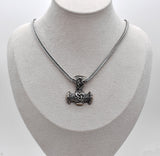 Thorshammer-Kette aus 925er Sterling Silber

Der massiv gearbeitete Thorshammer aus 925er Sterling Silber ist der Mittelpunkt dieser nordisch inspirierten Halskette.

Verschlungene Flechtornamente verzieren den Schaft des Mjölnir, während auf dem Hammerkopf eine Triskele sitzt. Die Vertiefungen sind dunkel abgesetzt und lassen die plastischen Details des Silberanhängers deutlich hervortreten.

Kombiniert ist der etwa 8,5 g schwere Anhänger mit einer 56 cm langen Fuchsschwanzkette aus Edelstahl. Geschlossen 