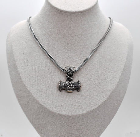 Thorshammer-Kette aus 925er Sterling Silber

Der massiv gearbeitete Thorshammer aus 925er Sterling Silber ist der Mittelpunkt dieser nordisch inspirierten Halskette.

Verschlungene Flechtornamente verzieren den Schaft des Mjölnir, während auf dem Hammerkopf eine Triskele sitzt. Die Vertiefungen sind dunkel abgesetzt und lassen die plastischen Details des Silberanhängers deutlich hervortreten.

Kombiniert ist der etwa 8,5 g schwere Anhänger mit einer 56 cm langen Fuchsschwanzkette aus Edelstahl. Geschlossen 