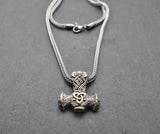 Thorshammer-Kette aus 925er Sterling Silber

Der massiv gearbeitete Thorshammer aus 925er Sterling Silber ist der Mittelpunkt dieser nordisch inspirierten Halskette.

Verschlungene Flechtornamente verzieren den Schaft des Mjölnir, während auf dem Hammerkopf eine Triskele sitzt. Die Vertiefungen sind dunkel abgesetzt und lassen die plastischen Details des Silberanhängers deutlich hervortreten.

Kombiniert ist der etwa 8,5 g schwere Anhänger mit einer 56 cm langen Fuchsschwanzkette aus Edelstahl. Geschlossen 