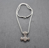 Thorshammer-Kette aus 925er Sterling Silber

Der massiv gearbeitete Thorshammer aus 925er Sterling Silber ist der Mittelpunkt dieser nordisch inspirierten Halskette.

Verschlungene Flechtornamente verzieren den Schaft des Mjölnir, während auf dem Hammerkopf eine Triskele sitzt. Die Vertiefungen sind dunkel abgesetzt und lassen die plastischen Details des Silberanhängers deutlich hervortreten.

Kombiniert ist der etwa 8,5 g schwere Anhänger mit einer 56 cm langen Fuchsschwanzkette aus Edelstahl. Geschlossen 