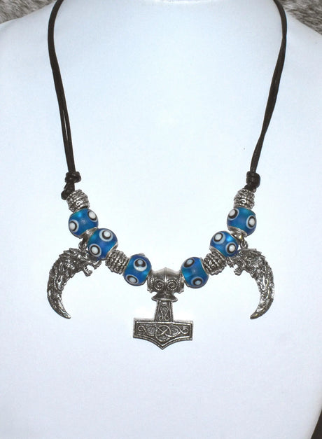 Mjölnir-Kette „Ragnar“ kombiniert drei Anhänger aus 925er Sterling Silber mit kräftig blauen, handgefertigten Glasperlen und schwarzem Lederband.

Im Mittelpunkt sitzt ein reich verzierter Thorshammer. Zwei gebogene, zahnförmige Anhänger mit plastisch ausgearbeiteten Wolfsköpfen flankieren den Mjölnir.
