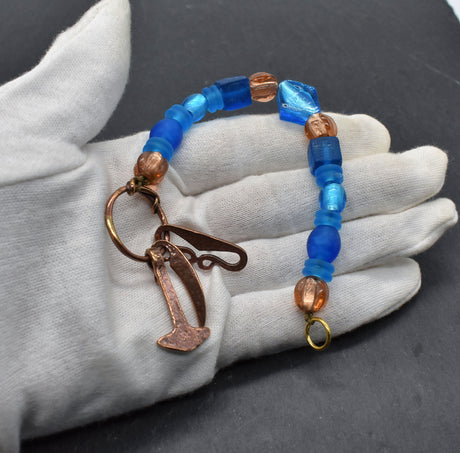 Authentischer Wikingerschmuck aus Bronze mit Mjölnir, Feuerstein und Druidensichel. Handgefertigte Fibelketten aus Glasperlen in blau und lachs – ideal für Reenactment, LARP und Mittelalterfans.