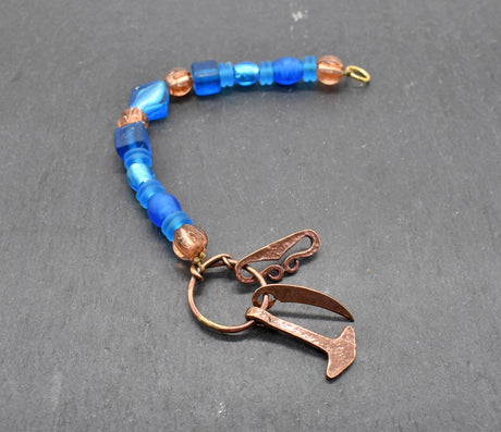 Authentischer Wikingerschmuck aus Bronze mit Mjölnir, Feuerstein und Druidensichel. Handgefertigte Fibelketten aus Glasperlen in blau und lachs – ideal für Reenactment, LARP und Mittelalterfans.