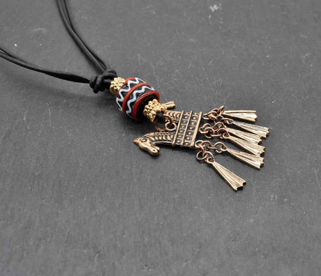 Keltische Halskette Echna aus Bronze, mit handgefertigter schwarzer Glasperle mit Muster aus rot und weiß, sowie vergoldeten Metallperlen an einem verstellbaren Lederband.