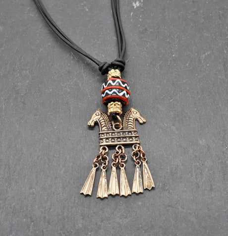 Keltische Halskette Echna aus Bronze, mit handgefertigter schwarzer Glasperle mit Muster aus rot und weiß, sowie vergoldeten Metallperlen an einem verstellbaren Lederband.