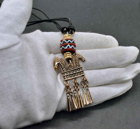 Keltische Halskette Echna aus Bronze, mit handgefertigter schwarzer Glasperle mit Muster aus rot und weiß, sowie vergoldeten Metallperlen an einem verstellbaren Lederband.