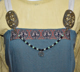 Tragebild am Wikingerkleid der Yggdrasil Fibelkette im Wikinger-Stil – Handgefertigt mit silberfarbenem Anhänger und Glasperlen in hellgrün und dunkellila