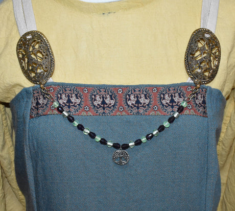 Tragebild am Wikingerkleid der Yggdrasil Fibelkette im Wikinger-Stil – Handgefertigt mit silberfarbenem Anhänger und Glasperlen in hellgrün und dunkellila